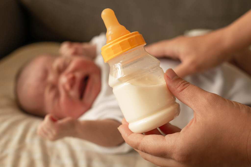 A parent trying to confort and feed a crying screaming baby