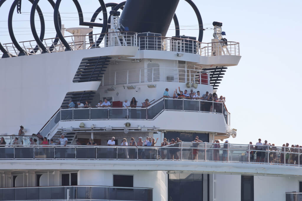 Relaxed, happy and excited cruise ship passengers waving as they sail away