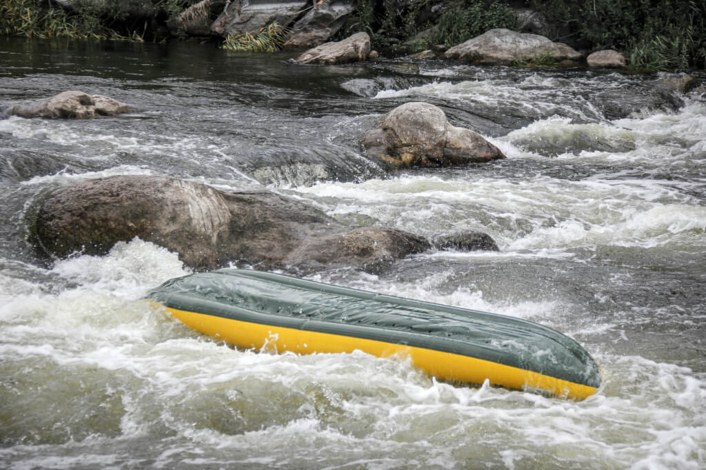 Kayakers fights the white water in a Pivdenny Bug river. They and their kayak are flipping over in the the wild water. Kayak bottom up