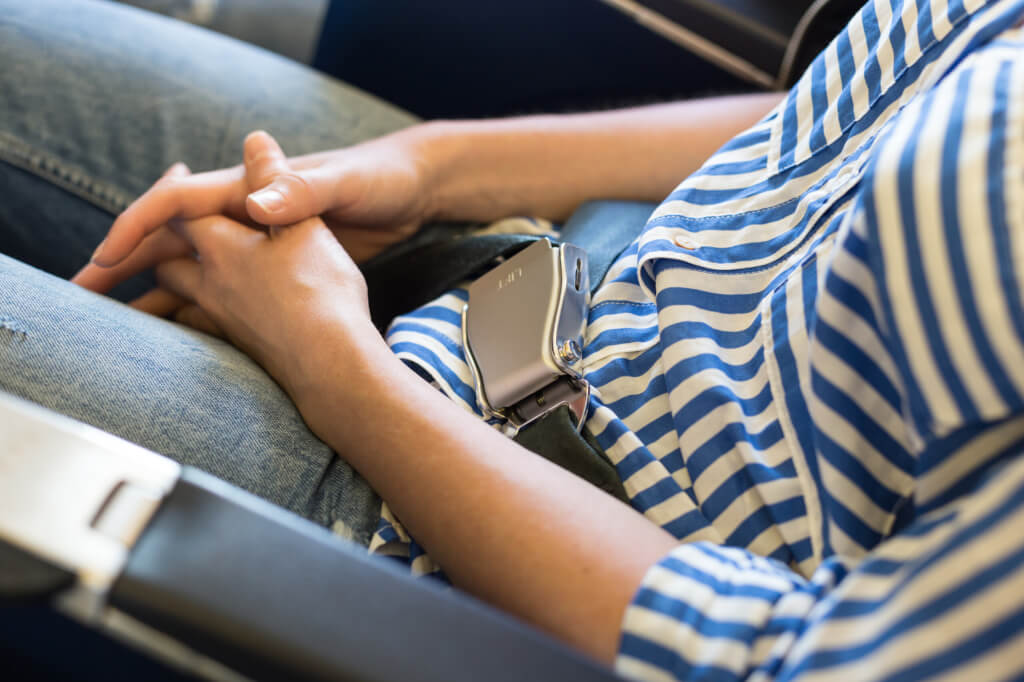 Female passenger with seat belt fastened while sitting on airplane for safe flight